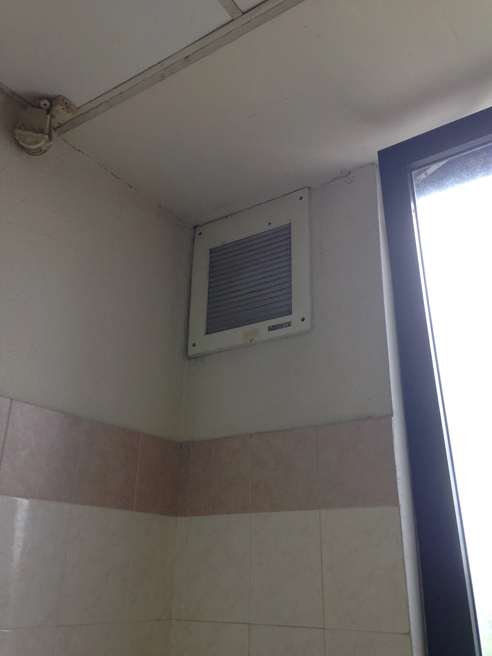 Wall-mounted extractor grille beside a window