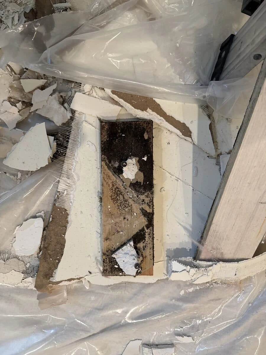 Opened ceiling finish revealing a pipe and affected material
